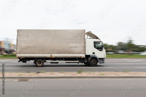 A white truck is driving down the street. Motion blur
