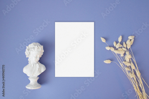 Blank greeting card mock up with dry grass and statue on the blue background
