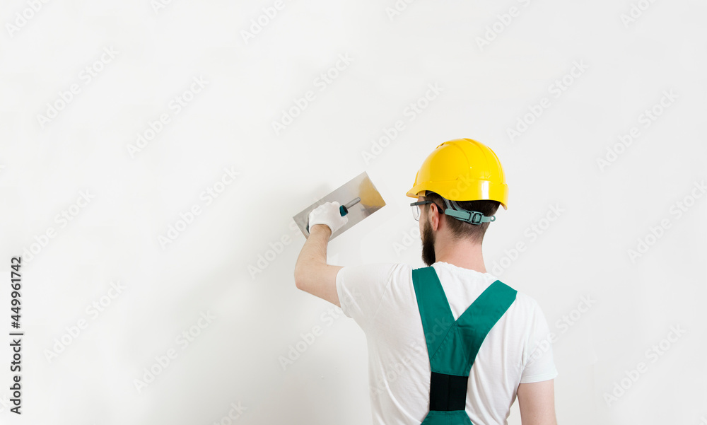 Back view of Caucasian worker with helmet, plastering wall, copy space Back view of Caucasian worker with helmet, plastering wall, copy space
