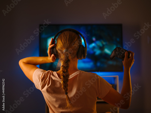 Video game. The girl plays a video game with a joystick. Night time. Home furnishings. Day off. Hobby, gambling addiction. Gaming business. Color image.