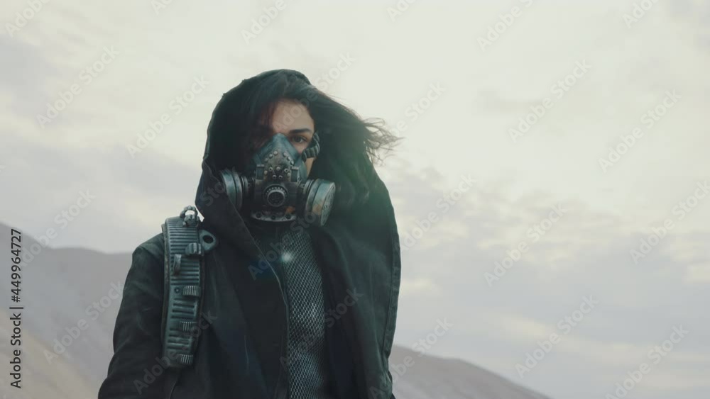 Portrait woman in grunge clothes hooded mantle and protective gas mask posing by white desert hills looking into camera. Future female survivor. Post apocalyptic world. Steadicam following shot Portrait woman in grunge clothes hooded mantle and protective gas mask posing by white desert hills looking into camera. Future female survivor. Post apocalyptic world. Steadicam following shot