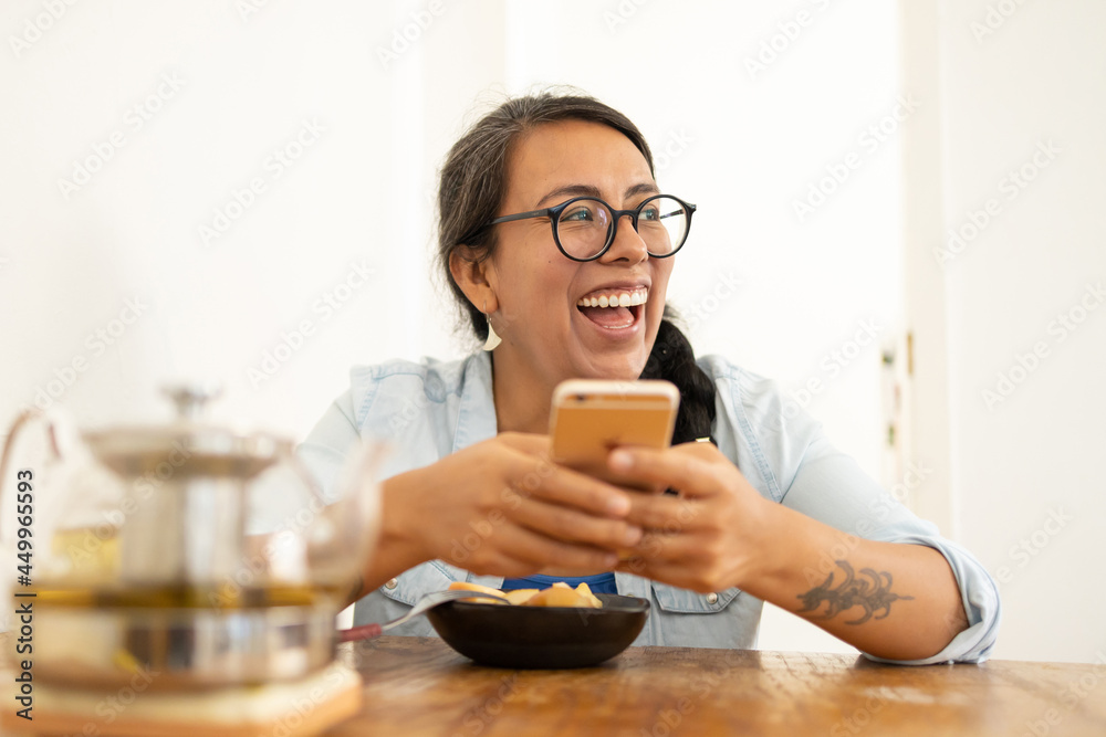 woman texting while having fruit breakfast and laughing woman texting while having fruit breakfast and laughing