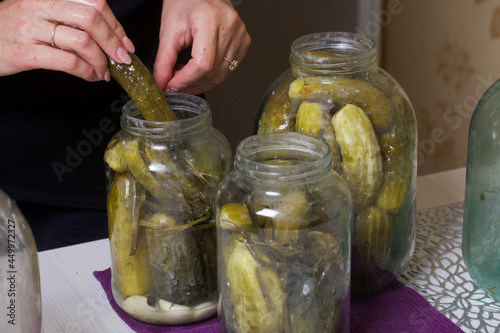 A woman pours boiling marinade over cucumbers in jars. Pickling cucumbers at home. Vegetable harvest conservation. Close-up shot.