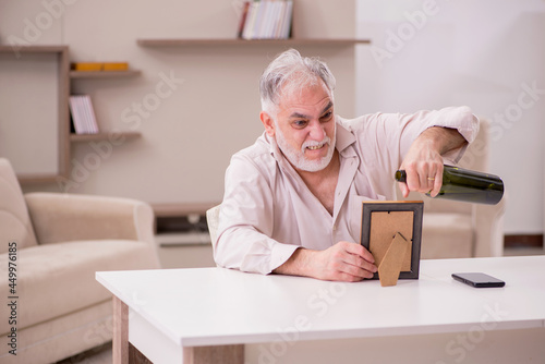 Fotografia Old widower drinking alcohol at home