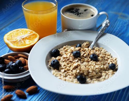 Healthy breakfast, food and diet concept - oatmeal with fresh berries on white plate with orange juice and milk