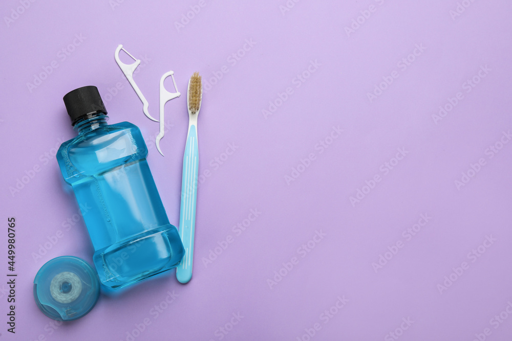 Mouthwash, toothbrush and dental floss on violet background, flat lay. Space for text