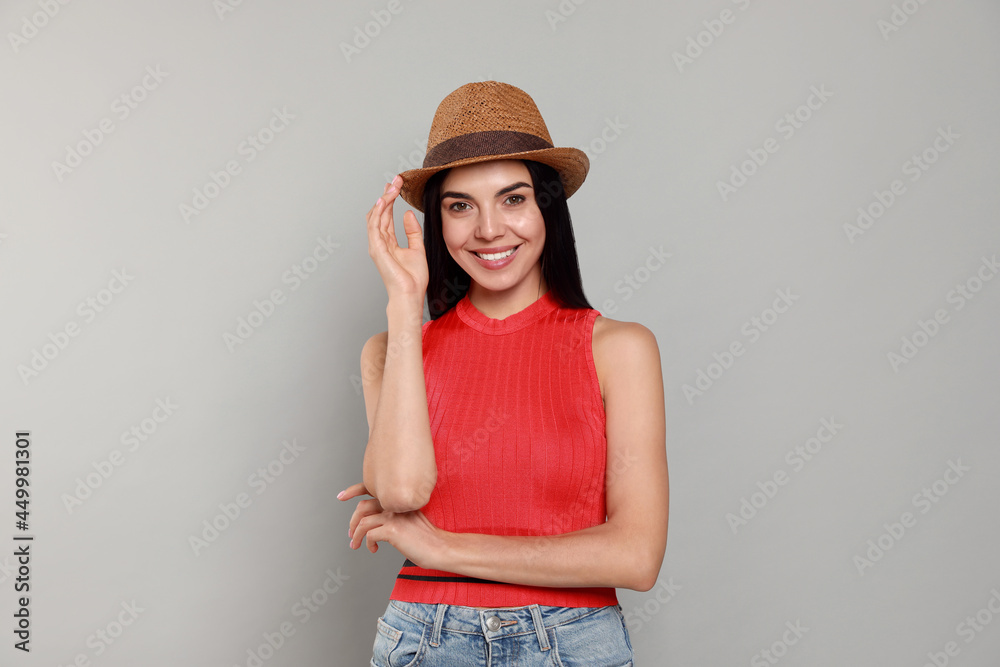 Beautiful young woman with straw hat on light grey background Beautiful young woman with straw hat on light grey background