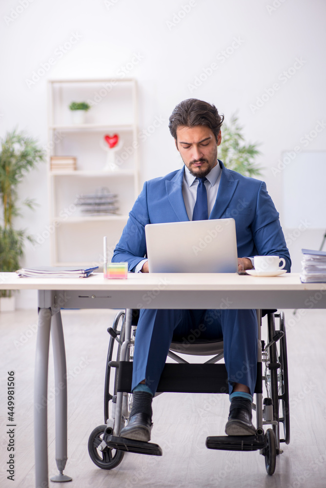 Young male employee in wheel-chair at workplace