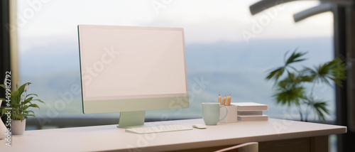 Working table, computer monitor mockup near window and nature view outdoor