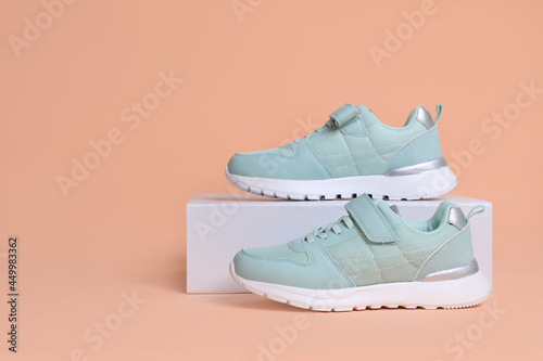Fototapeta Naklejka Na Ścianę i Meble -  Pair of comfortable sports shoes and box on pale coral background. Space for text