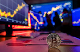 Silver bitcoin cryptocurrency token on desk in front financial analysis graph chart trading growth report on computer and laptop screen while broker meeting in shadow blurred background