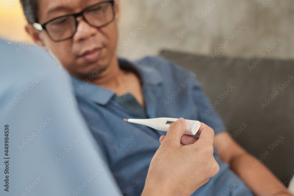 Close-up shot of thermometer in female doctor's hand while taking temperature, examination Asian male senior patient. It is home medical service and healthcare for retired elderly people. Close-up shot of thermometer in female doctor's hand while taking temperature, examination Asian male senior patient. It is home medical service and healthcare for retired elderly people.