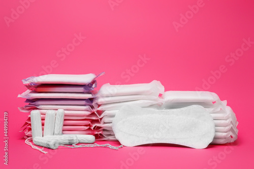 Many menstrual pads and tampons on pink background photo