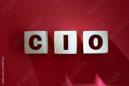 CIO written on wooden cubes - arranged in a vertical pyramid, red background, CIO - short for Chief Information Investment Officer, business concept photo