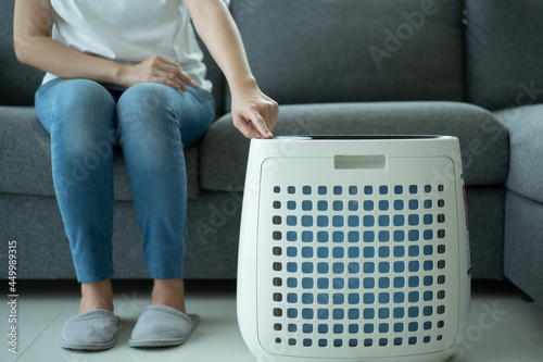 Asian woman turning on the modern air purifier while staying in the living room.