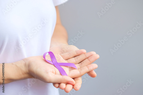 Hand holding purple Ribbon for Pancreatic, Esophageal, Testicular cancer, world Alzheimer, epilepsy, lupus, Sarcoidosis, Fibromyalgia and domestic violence Awareness month. World cancer day concept