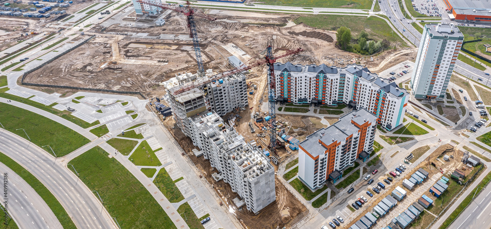 Fototapeta premium aerial top view of city area under construction with residential buildings and working tower cranes. panoramic aerial photo.