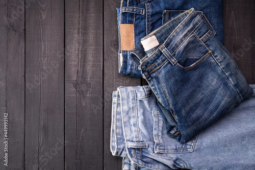 Blue jeans resting on a dark black wooden table. Modern fashion jeans - top view with space to copy text.