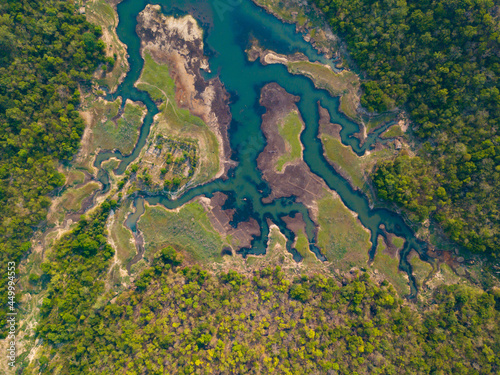 Aerial top view of barren lake surrounded by forest in summer.