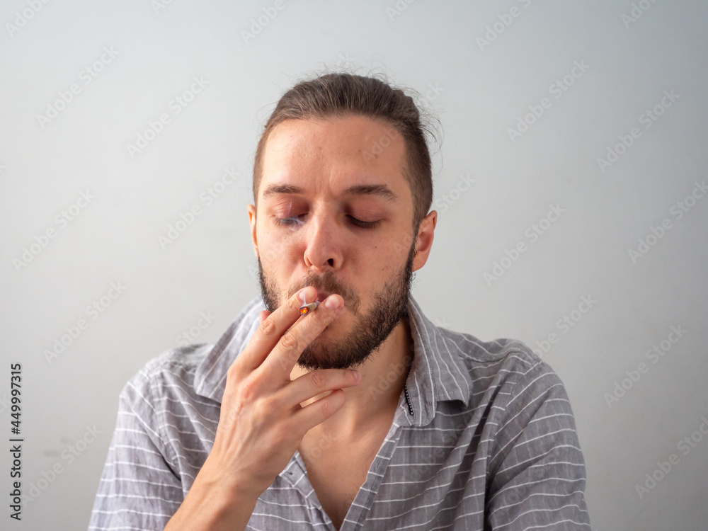 Caucasian Man in Gray Shirt Smokes a Cigarette in White Room in Medellin, Colombia