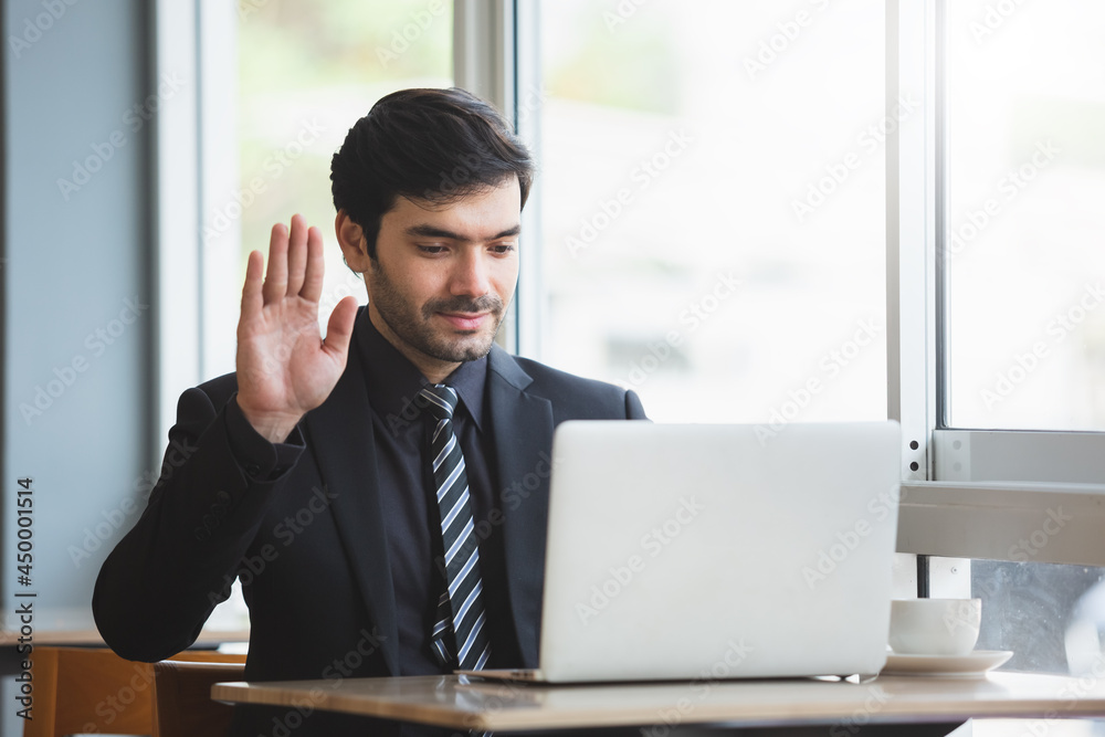 businessman raising hand to greet making video call on laptop. conference online. working new normal. Man working on computer laptop. businessman raising hand to greet making video call on laptop. conference online. working new normal. Man working on computer laptop.