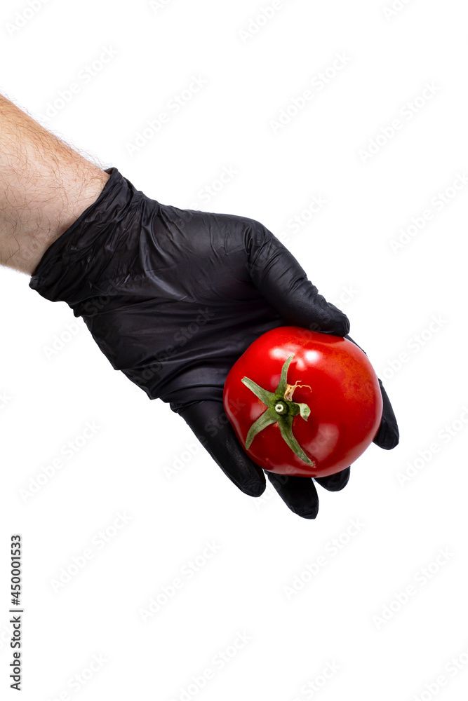 Bright red tomato in the hand of a man in a black glove on a white isolated