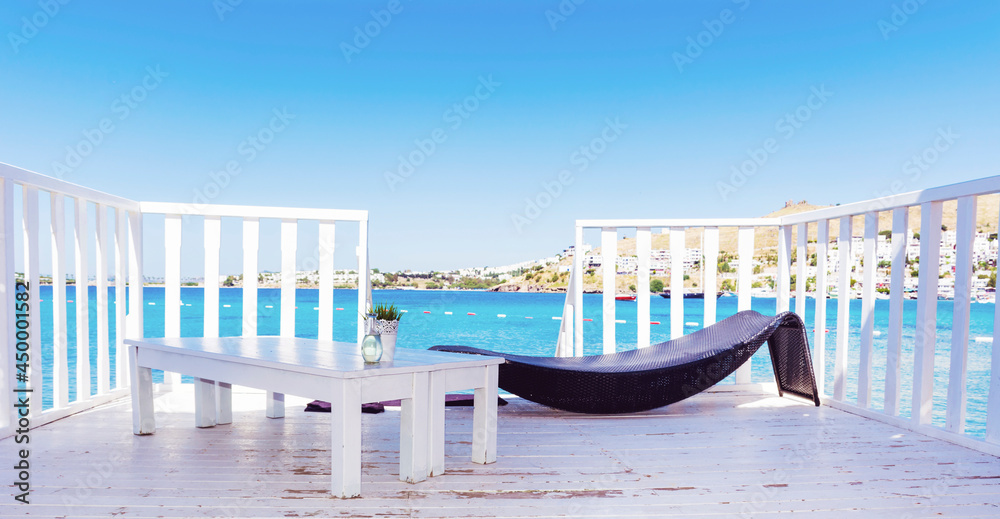 Relaxing Rattan Sunbed and White Wooden Table with Sea View .Private Beach above the Sea