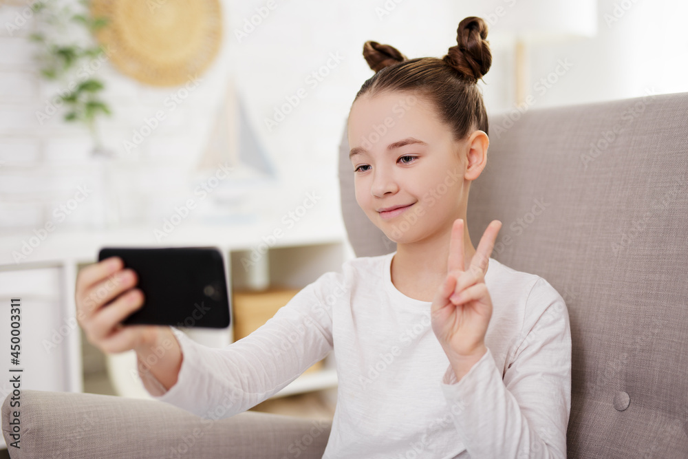 technology, social media and internet concept - cute school girl taking selfie photo with smartphone at home technology, social media and internet concept - cute school girl taking selfie photo with smartphone at home