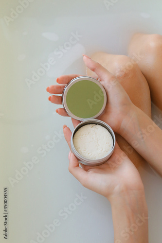 Top view of woman hands with solid soap on white water background, taking bath
