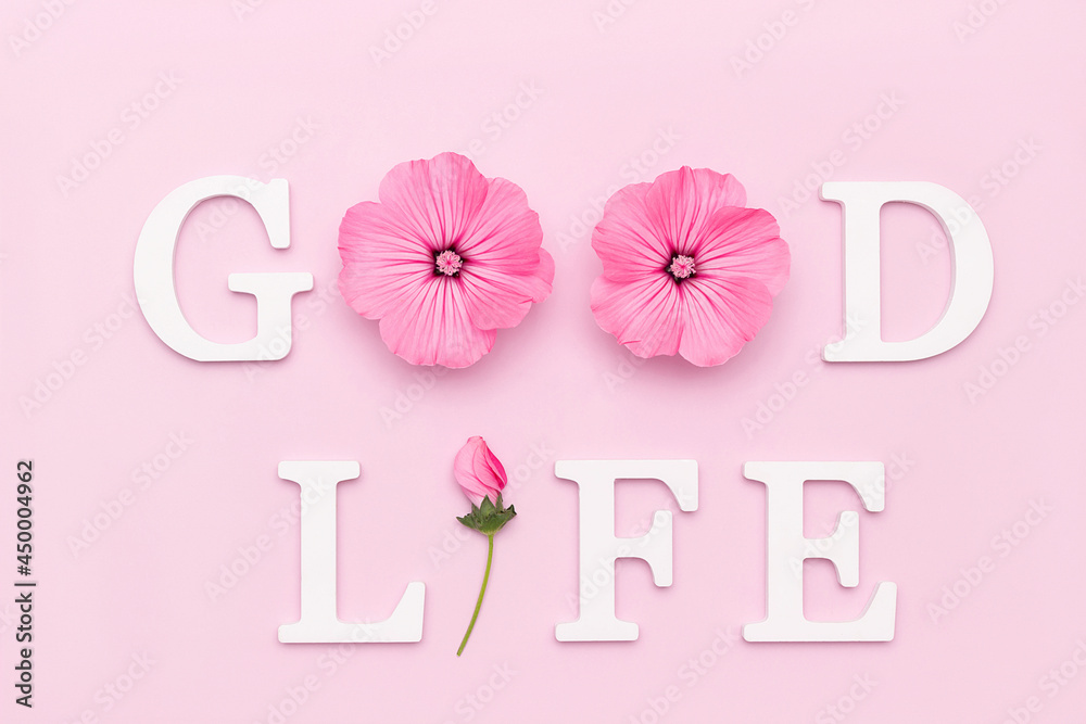 Good life. Motivational quote from white letters and beauty natural flowers on pink background. Creative concept inspirational quote of the day
