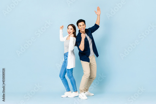 Konstfotografi Full length portrait of cheerful Asian couple standing back to back smiling and