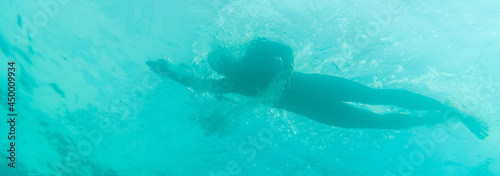 Silhouette of an athlete swimming in beautiful blue water