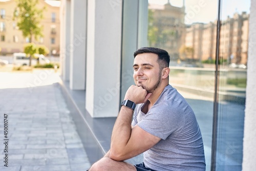 athletic sexy young caucasian male with dark hair sitting in front of a building and resting his hand on his chin Free Download athletic sexy young caucasian male with dark hair sitting in front of a building and resting his hand on his chin - GFXLoad