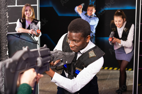 Portrait of African Americanbusinessman playing laser tag with his co-workers in dark room