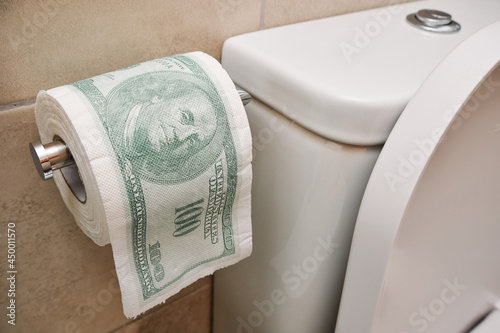 Toilet roll with US dollar bill printed - senseless wasting money financial crisis concept photo