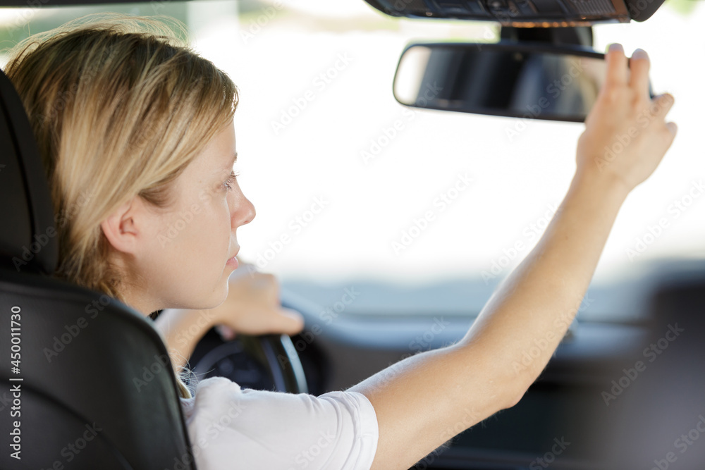 woman adjusting rear view mirror woman adjusting rear view mirror