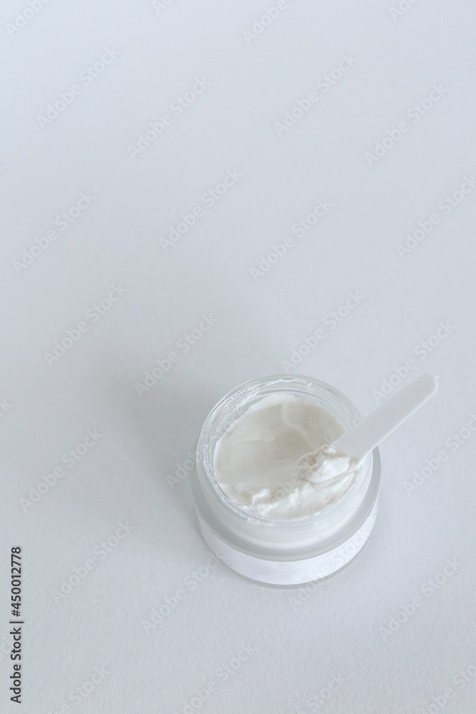 Moisturizing cosmetic cream with eucalyptus stands on neutral background with milk splash
