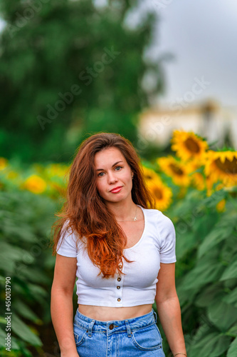 Portrait of a cute young woman in a field of sunflowers. Beautiful summer concept