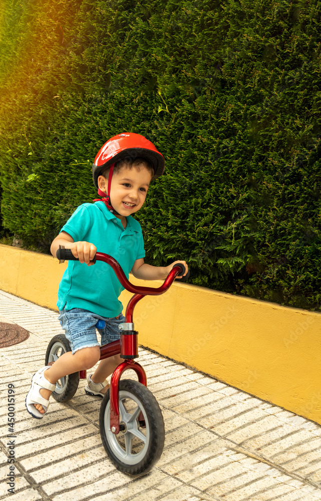 preschooler smiling and playing with a small bike on a sunny day preschooler smiling and playing with a small bike on a sunny day