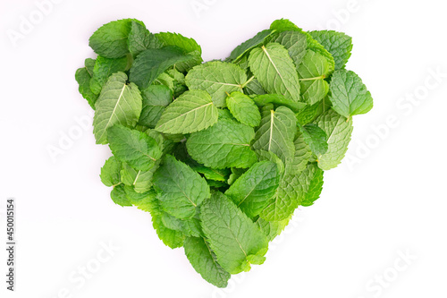 A lot of mint leaves in the shape of a heart on a white background. Flat lay.