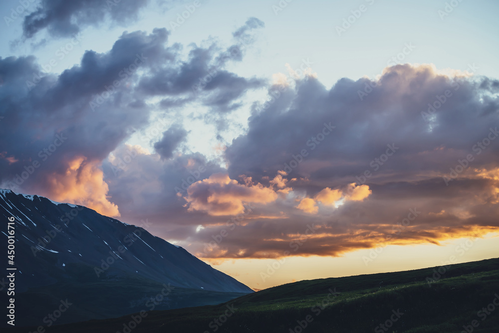 Atmospheric mountain scenery with lilac dawn sky. Scenic landscape with illuminating sunset in mountains. Beautiful sunrise in mountains in pastel tones. Illuminating color in dawn cloudy sky.