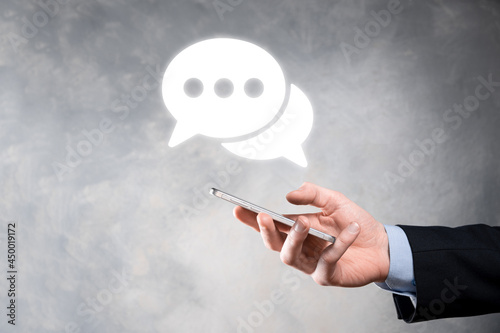 Businessman holding a message icon, bubble talk notification sign in his hands. Chat icon, sms icon, comments icon, speech bubbles