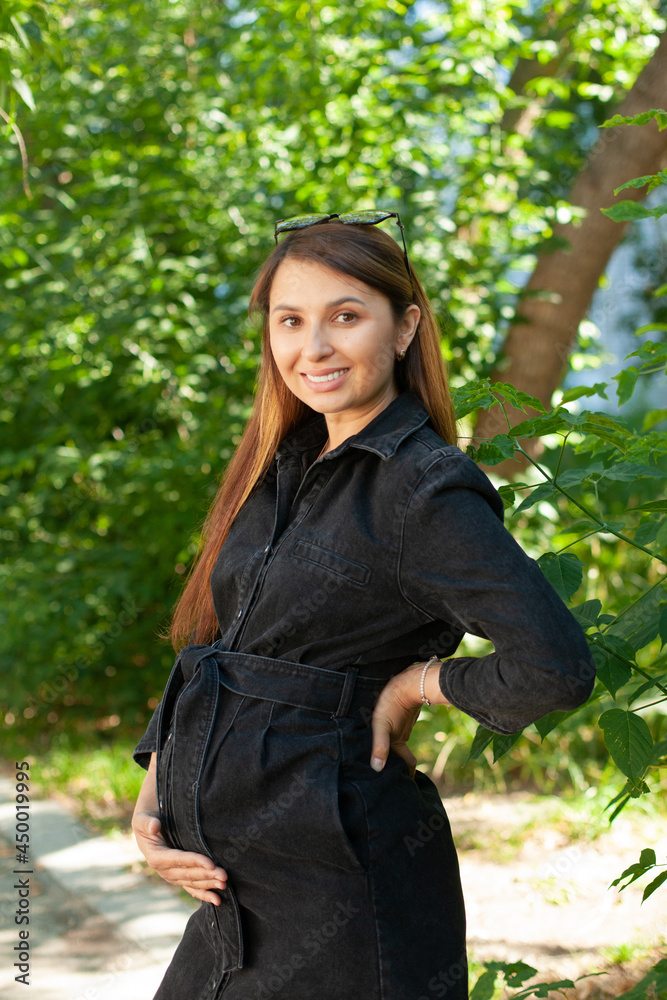 A beautiful stylish pregnant woman walks in the park. Fresh air, healthy lifestyle. Nature. A beautiful stylish pregnant woman walks in the park. Fresh air, healthy lifestyle. Nature.