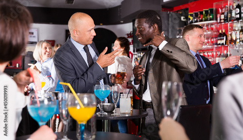 Portrait of African and Caucasian men having fun and talking on the corporate party
