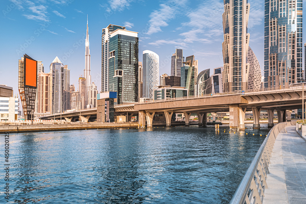 Fototapeta premium Scenic view of high skyscrapers with offices, hotels and residential buildings in UAE. Road over the bridge and flyover passes through the Dubai Creek Canal