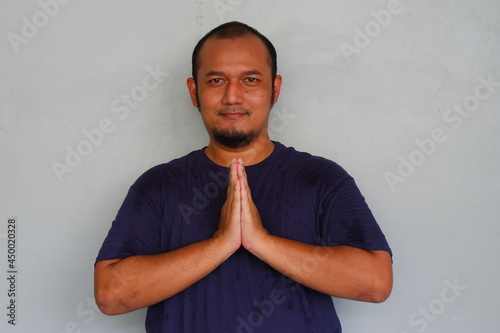 Young asian man smiling face and hand praying gesture