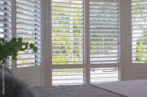 Luxury white indoor plantation shutters in bedroom - selective focus photo