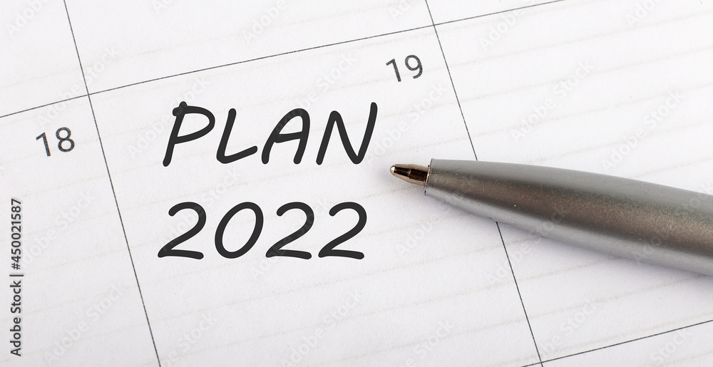 Text PLAN 2022 on calendar planner to remind you an important appointment with a pen on isolated white background. Text PLAN 2022 on calendar planner to remind you an important appointment with a pen on isolated white background.