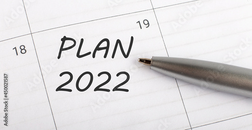 Text PLAN 2022 on calendar planner to remind you an important appointment with a pen on isolated white background.