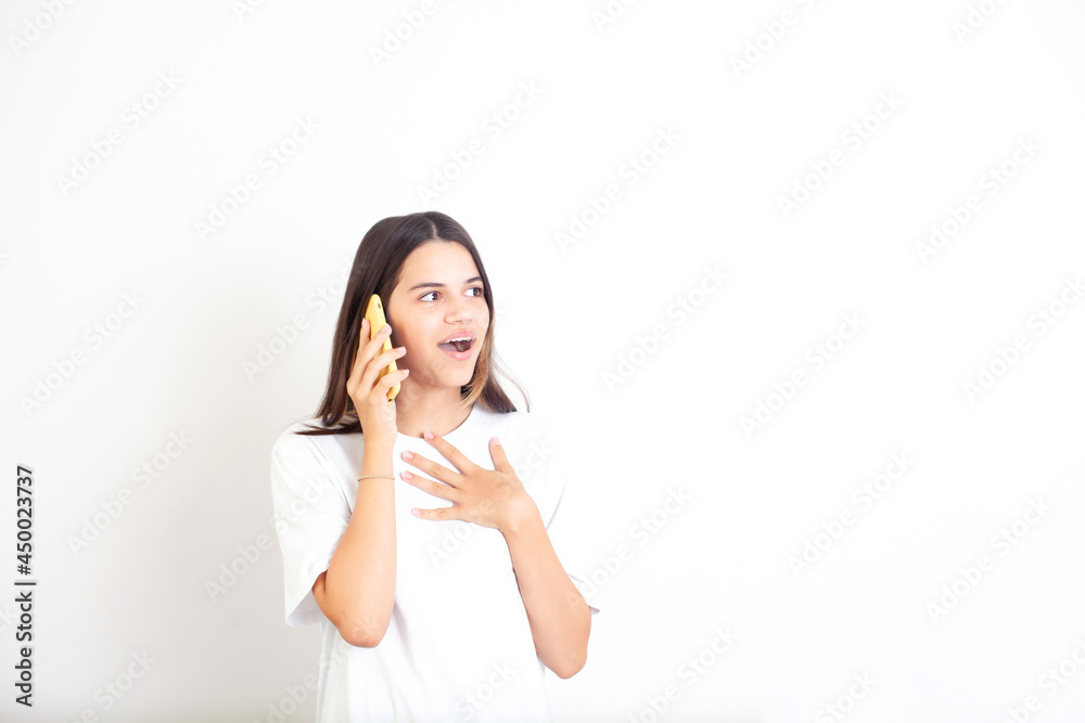 A teenage girl talks on the phone and is surprised. White background, space for text. Communication, conversation, call. Social networks. Contacts A teenage girl talks on the phone and is surprised. White background, space for text. Communication, conversation, call. Social networks. Contacts